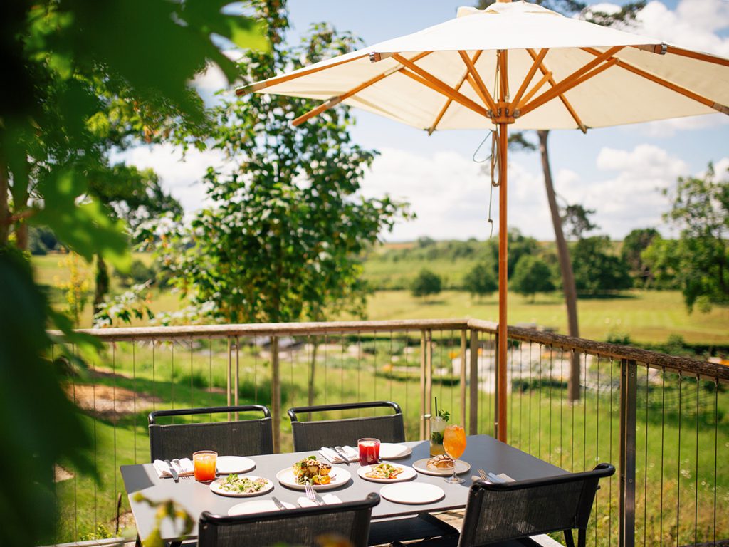 A terrace table at the Garden Café set for a summer lunch with views overlooking The Newt's garden