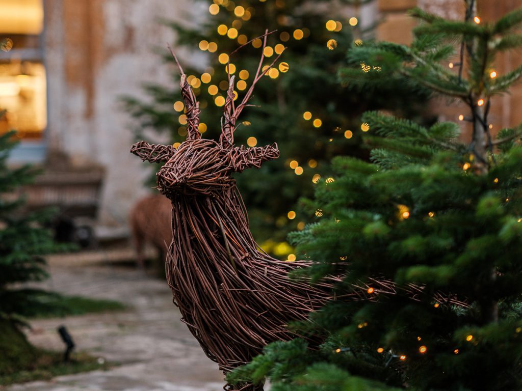 Christmas creatures in willow set against a background of glowy Christmas trees