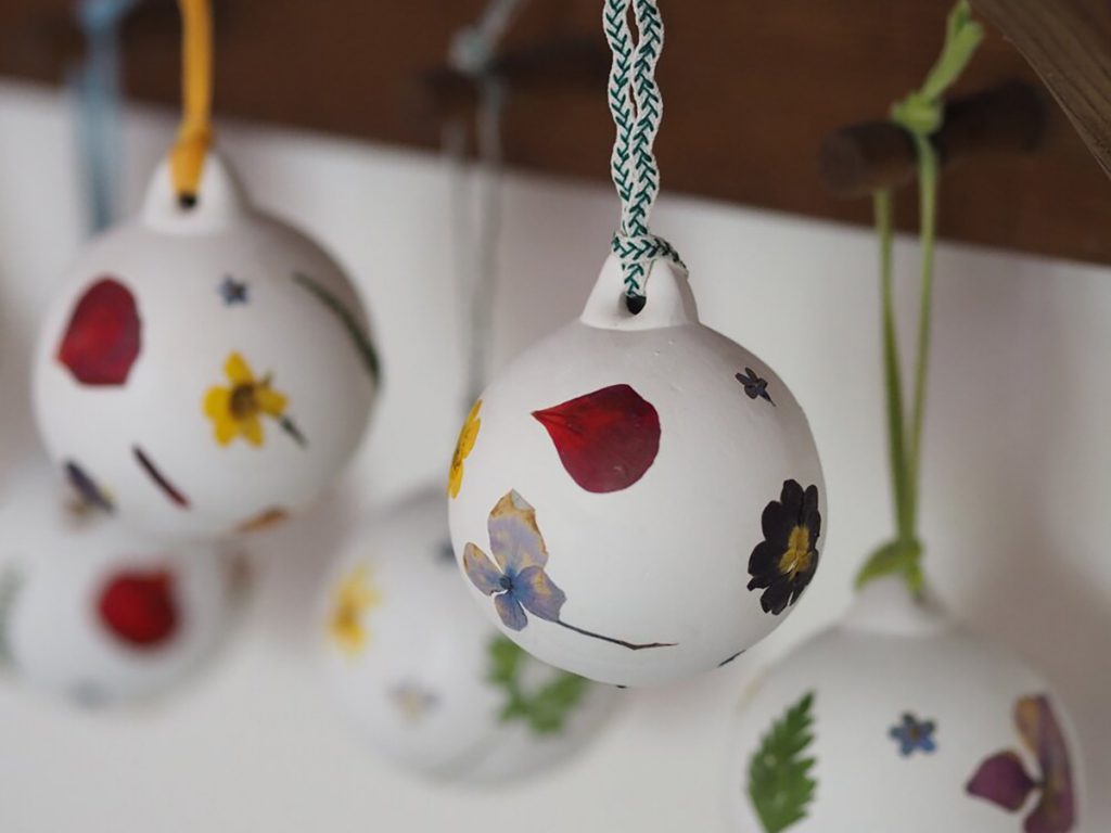 White ceramic baubles decorated with pressed flowers